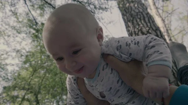 Mãe em seus braços levanta o bebê no ar . — Fotografia de Stock