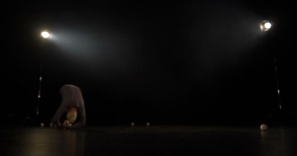 4k повільний рух жонглер в чорній студії робить трюк з одним м'ячем . — стокове відео