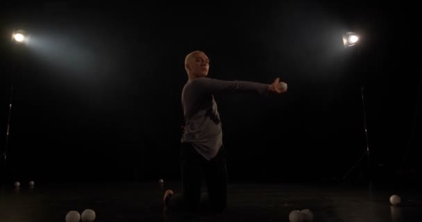 4k lassú mozgás-zsonglőr a fekete stúdióban, hogy trükk egy labdát. — Stock videók