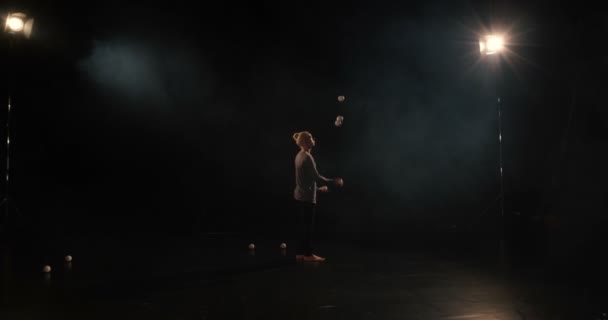 4K-Juggler w czarnym studiu sprawia, że sztuczki z pięcioma piłkami. — Wideo stockowe