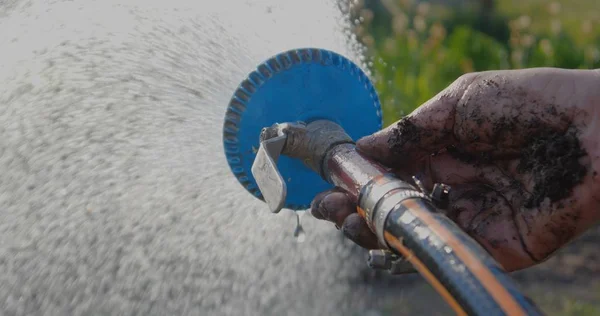 Streams of water flowing from a shower head kept by a hand in a garden — Stock Photo, Image