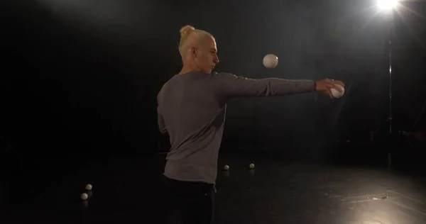 Juggler dans le studio noir faire des tours avec des boules . — Photo