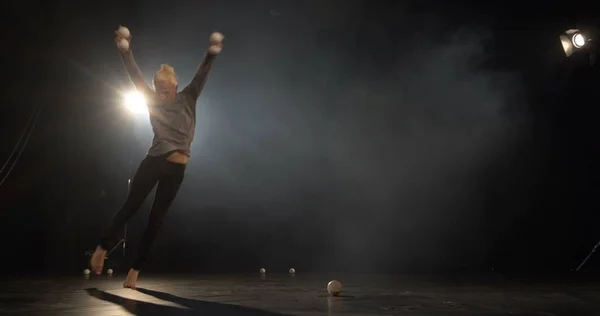 De jongleur in de zwarte Studio maken truc met vier ballen. — Stockfoto