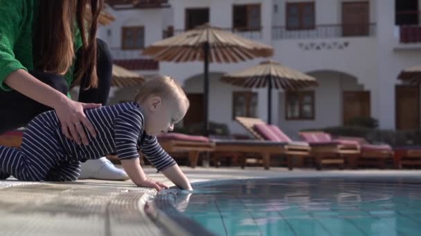Η μαμά με το μωρό κοντά στην πισίνα, το μωρό αγγίζει το νερό σε αργή κίνηση — Αρχείο Βίντεο