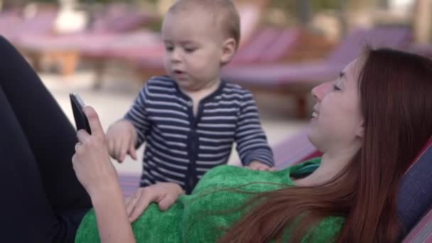Máma ukazuje dítěti něco na telefonu a pomalu se usmívá — Stock video