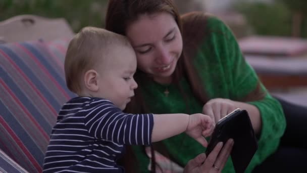 Vážný malý chlapec se svou matkou, který v pomalém pohybu tleskal smartphone — Stock video