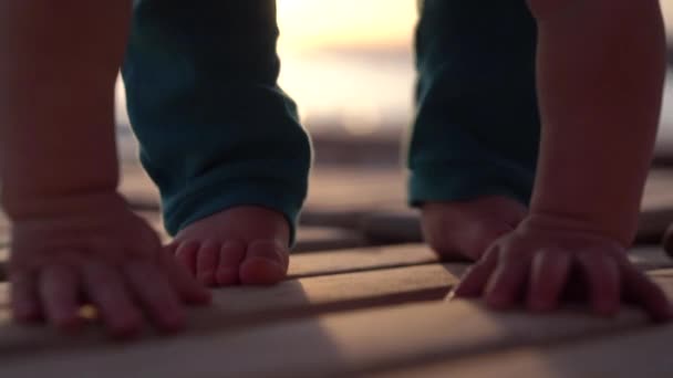 Piccolo bel bambino che striscia su un lettino di legno vicino al mare durante il tramonto — Video Stock