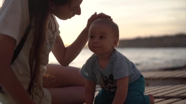 Anne öpücük bir sevimli bebek gün batımı içinde yavaş hareket — Stok video