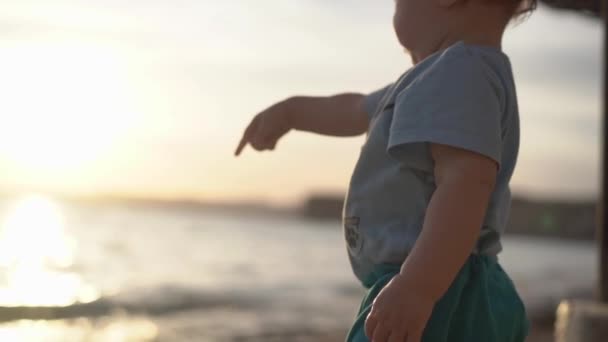 Un bébé montre de l'intérêt pour quelque chose près de la mer par son doigt au ralenti — Video