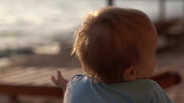 De baby is geïnteresseerd in iets van bovenaf in slow motion — Stockvideo