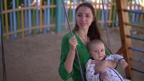 Glimlachende moeder en kleine baby Ride op een schommel in slow motion — Stockvideo