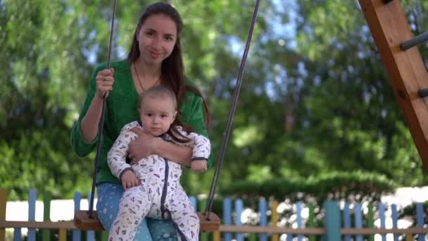 Jovem mãe e bebê passeio em um balanço em câmera lenta — Vídeo de Stock