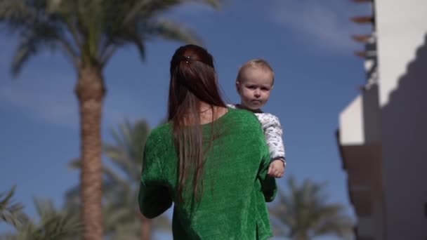 Uma menina carrega um bebê e diz-lhe algo em câmera lenta — Vídeo de Stock