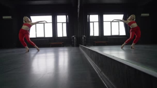 Sexy chica rubia baila en el estudio cerca del espejo . — Vídeo de stock