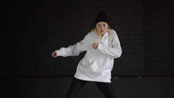 Cámara lenta - chica que baila hip hop en ropa blanca en la habitación con pared negra . — Vídeos de Stock