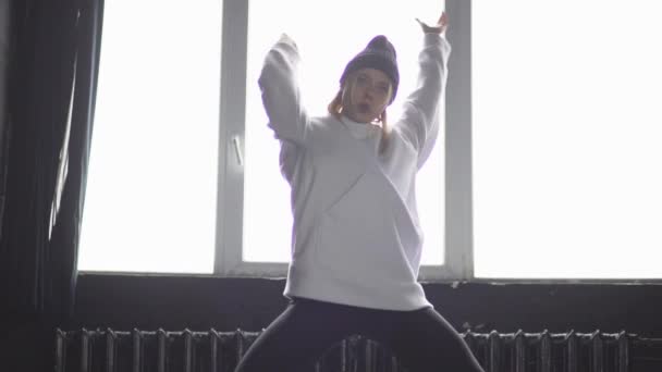 Молода і стильна дівчина в білому одязі танцює хіп-хоп у повільному русі . — стокове відео