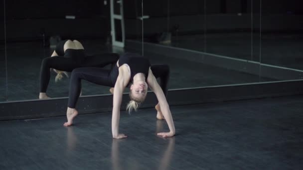 Blond danser in de studio in de buurt van spiegel maakt brug, — Stockvideo