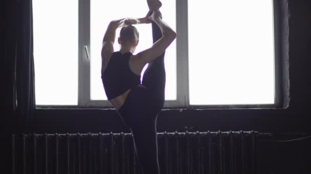 Junge blonde Tänzerin macht Spaltung auf einem Bein in Zeitlupe. — Stockvideo