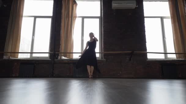 Κορίτσι σε μαύρο φόρεμα κάνει αστεία χορευτική κίνηση κοντά σε παράθυρο σε αργή κίνηση. — Αρχείο Βίντεο