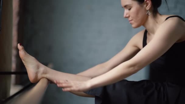 Ballerinentänzerin im schwarzen Kleid macht Stretching und lächelt in Zeitlupe. — Stockvideo