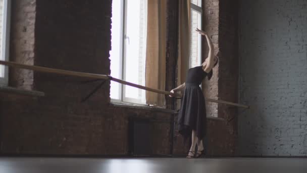 Siyah elbiseli kadın balo salonu penceresinde yakınındaki bale hareketi yapar. — Stok video