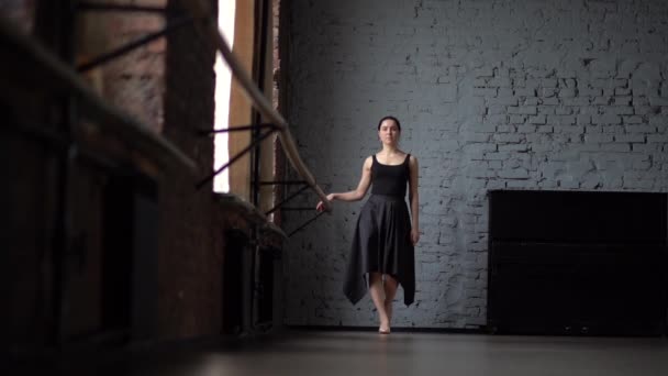 黒のドレスの少女がダンス スタジオでスローモーションで歩く. — ストック動画
