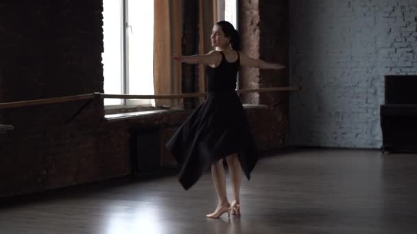 Grace dáma v černých šatech dělá obrací v tanečním studiu. — Stock video