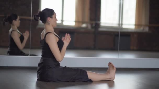 Stijlvolle vrouw in zwarte jurk maakt slop in yoga - slow motion. — Stockvideo