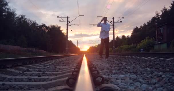 4k-gentalman kunstenaar maakt truc op de spoorweg bij zonsondergang. — Stockvideo