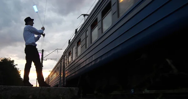 Художник на заході сонця робить небезпечний трюк на залізниці біля поїзда руху . — стокове фото