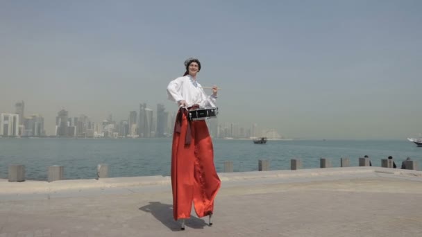 Ucraniano hombre en un traje popular jugando en un tambor en un muelle de mar en slo-mo — Vídeos de Stock