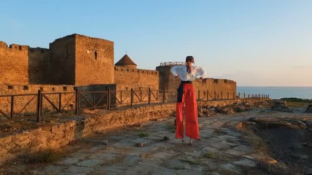 Man in a Ukrainian folk costume standing on stilts at a fortress in slo-mo — Stock Video