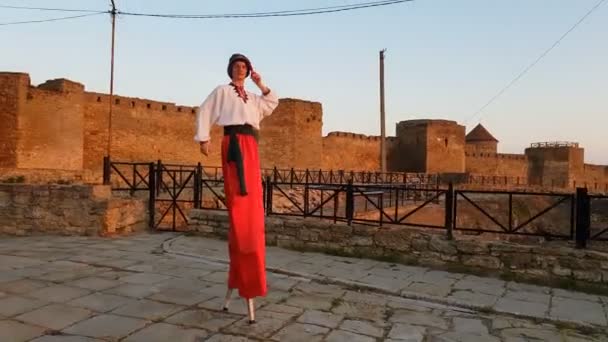 Man i en ukrainsk kostym marscherar på styltor på fästning på sommaren i slo-mo — Stockvideo