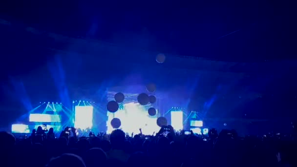 Tusentals människor tittar på en rock konsert och kastar ballonger i slo-mo — Stockvideo
