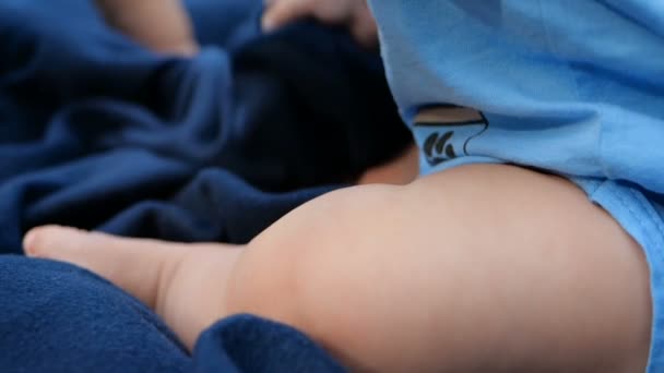 Cheery kids legs sitting on a dark blue sheet on a green meadow in slo-mo — Stock Video