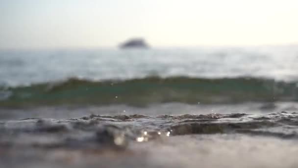 The waves wash the shore and in the background slowly sailing yacht. — Stock Video