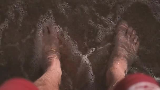 4k - вид на ноги человека, который стоит в море . — стоковое видео