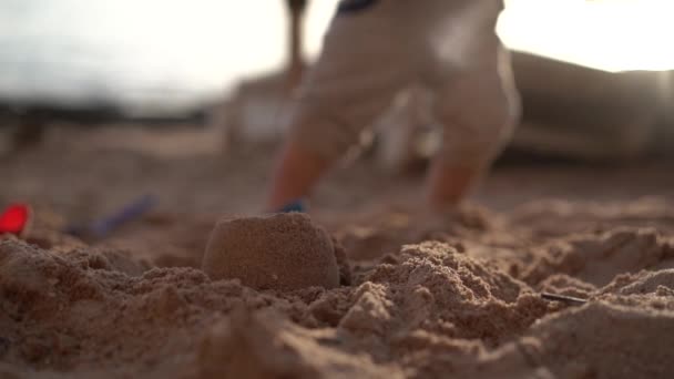 Bayi kecil di pantai dan ember merah dalam gerakan lambat . — Stok Video