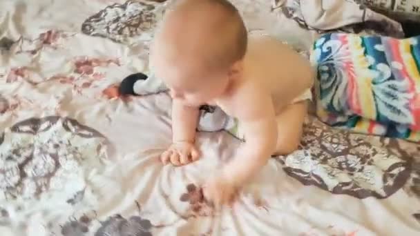 Fröhliches Kind, das in Socken auf einem großen Bett sitzt und in eine bewegliche Kamera blickt — Stockvideo