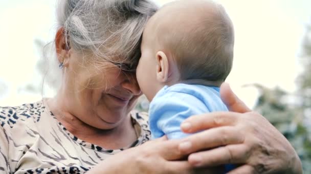 Alegre bebé sonriendo en las manos de su abuela en un día soleado en slo-mo — Vídeo de stock
