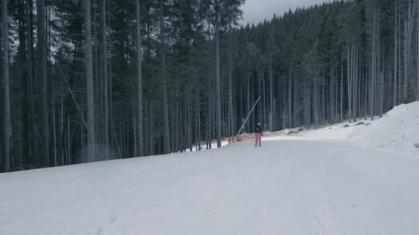 Счастливый турист в розовых штанах катается на лыжах по Карпатам зимой в сло-мо — стоковое видео