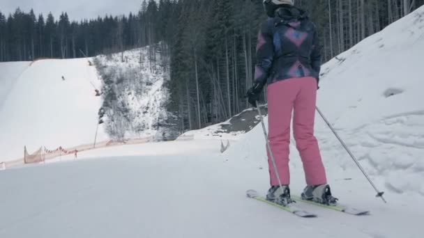 Vrouwelijke toerist uit te duwen met stokken en skiën in de Karpaten in slo-mo — Stockvideo