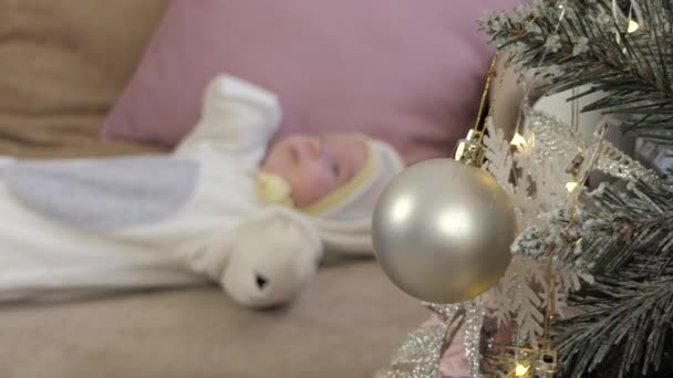 Um bebê recém-nascido está deitado no sofá perto da árvore de Natal . — Vídeo de Stock