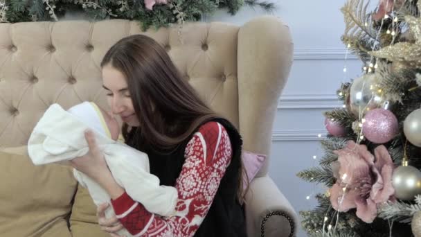 Árvore de Natal e mãe com bebê recém-nascido em suas mãos . — Vídeo de Stock