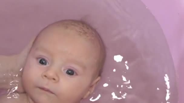 Schattige pasgeboren baby heeft een roze bad. — Stockvideo