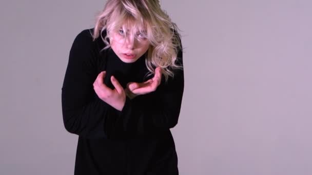 Flicka i en svart klänning som dansar med vinden i håret lockigt inomhus i slow motion — Stockvideo