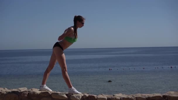 Chica delgada y deportiva hace yoga en la playa . — Vídeo de stock