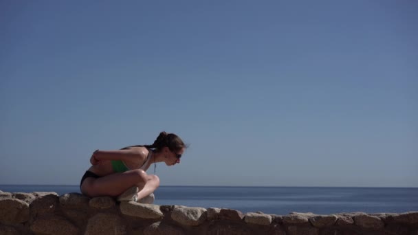 Ung och smal modell gör yoga på stranden av havet. — Stockvideo