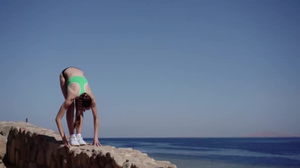 Sexy meisje maakt yoga helling in de buurt van de zee. — Stockvideo