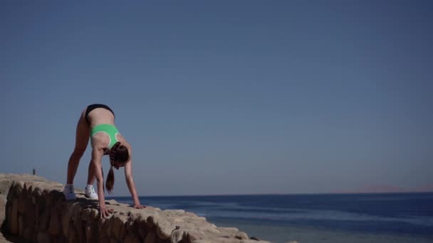 Sexy model maakt krijger pose van yoga op rotsachtige strand. — Stockvideo